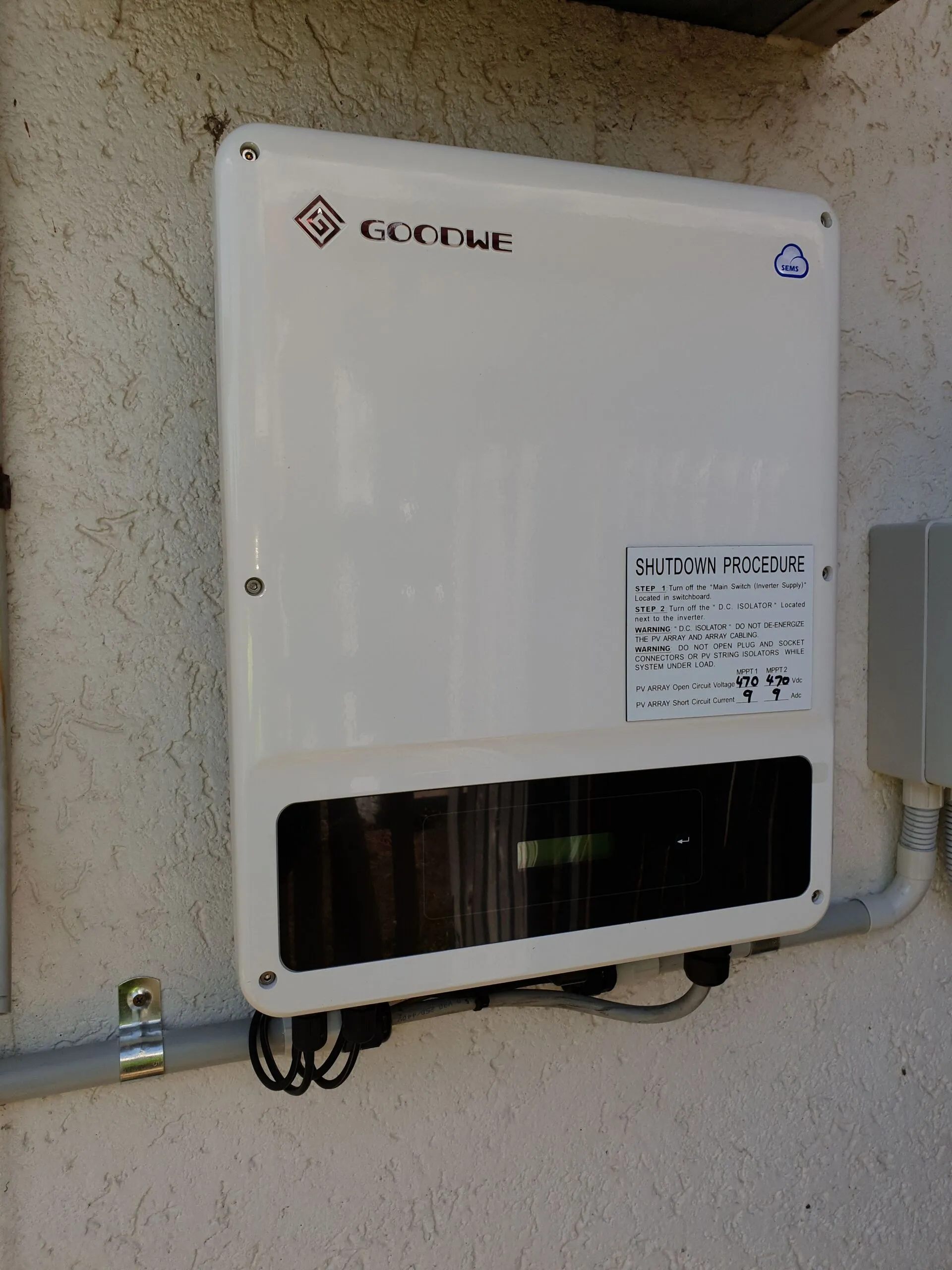 Best solar company Townsville checklist: a Goodwe inverter installed with its shutdown procedure label and conduit runs