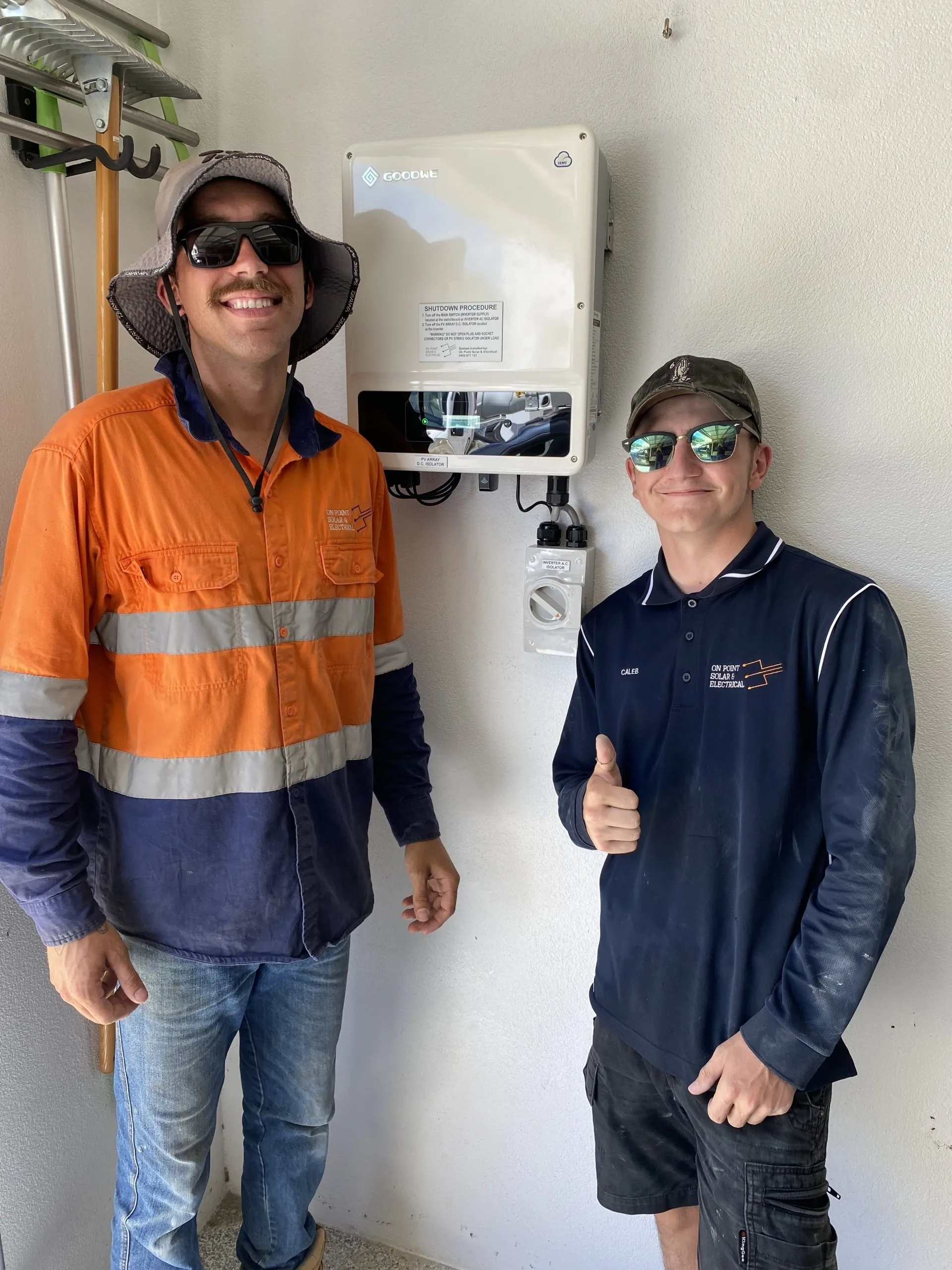Solar installers Townsville — the On Point Solar & Electrical team beside a Goodwe inverter they installed